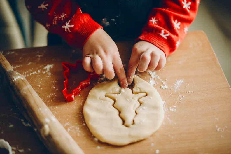 Zwei Kinder mit Weihnachtsmützen rühren in Schalen mit Teig.