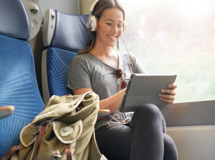 Young woman travelling by train with tablet and headphones