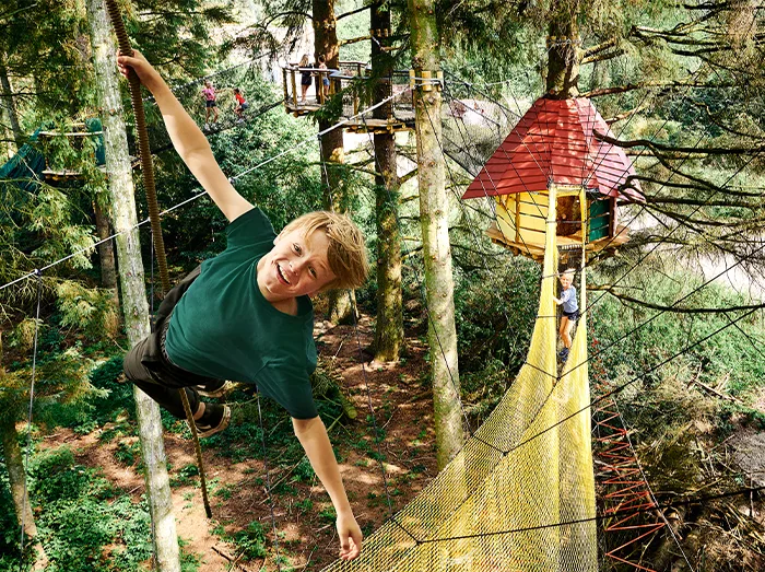 Ein Kind hat Spaß im Baumkronenparcours im WOW Park.