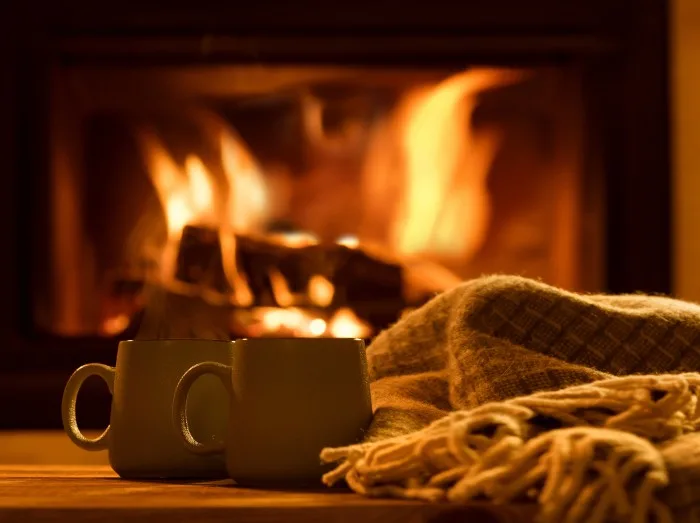 Steam from a cups with a hot cocoa on the fireplace background.