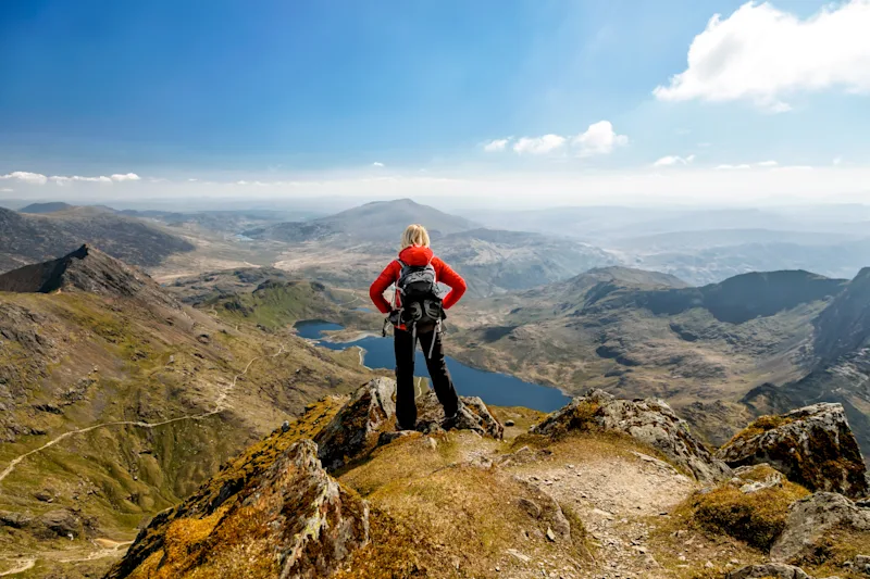 Young woman admiring the view from the summit of Mount Snowdon in Snowdonia National Park (Eryri National Park), Wales, UK