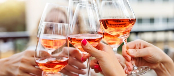 Close-up many female woman hands hold clinking rose wine glass celebrate toast party terrace warm sunset sun background.