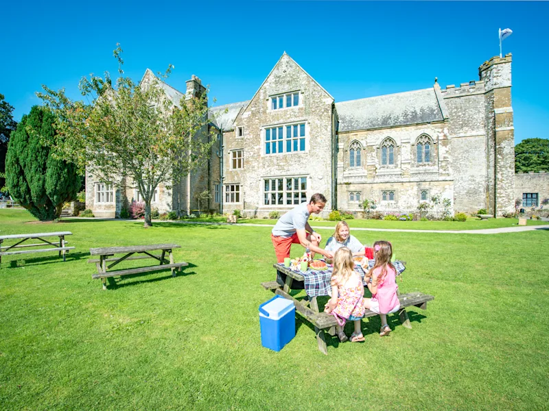 Family enjoying a picnic in the grounds of Trelawne Manor (TREL) in Looe, South Cornwall, England, UK