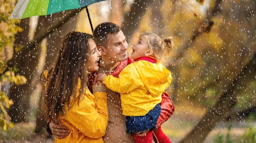 Happy family under a colourful umbrella in the rain