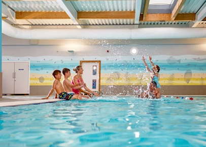 Family having fun in the indoor swimming pool at Piran Meadows Resort (SUML) in Newquay, England, UK
