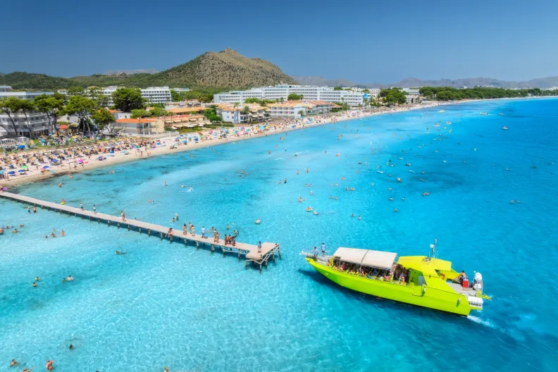 Ein Boot legt an einem Steg der Playa de Muro an.
