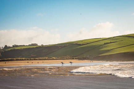 Surfers on Bigbury Beach at Burgh Island causeway, Bigbury-on-Sea, South Devon, UK