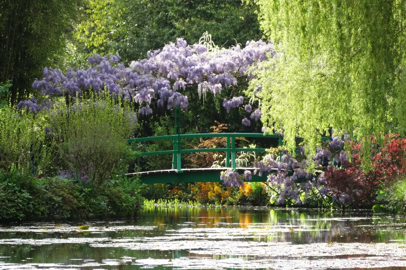 Brücke über einen See mit Blumen in Monets Garten in Giverny.