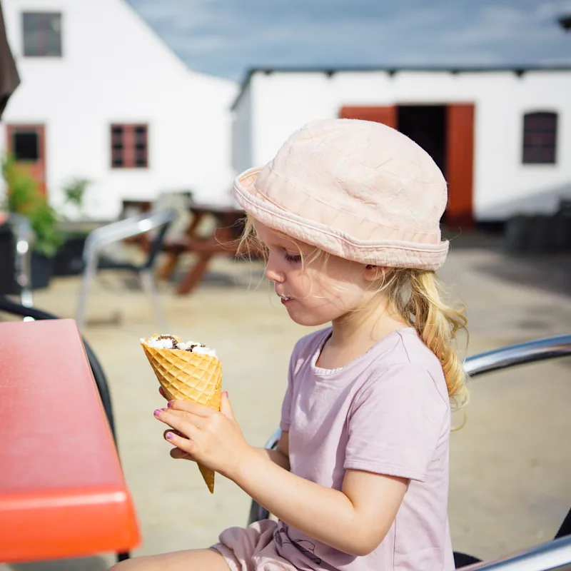 Ein Mädchen isst ein Eis in der Waffel auf Bornholm.