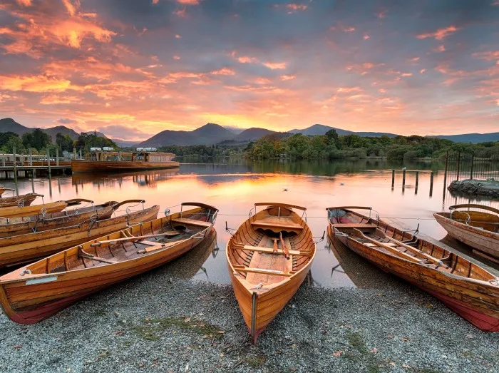 A fiery sunset over boats on the shore of Derwentwater at Keswick in the Lake District in Cumbria