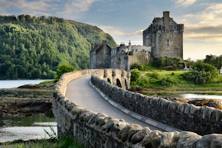 Evening light on restored Eilean Donan Castle on island at three lochs with added stone arch footbridge, Kyle of Lochalsh in the Scottish Highlands Scotland UK
