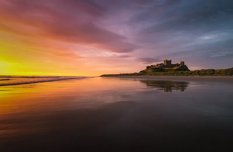 Bamburgh Beach and Bamburgh Castle at sunrise, Northumberland Coast, UK