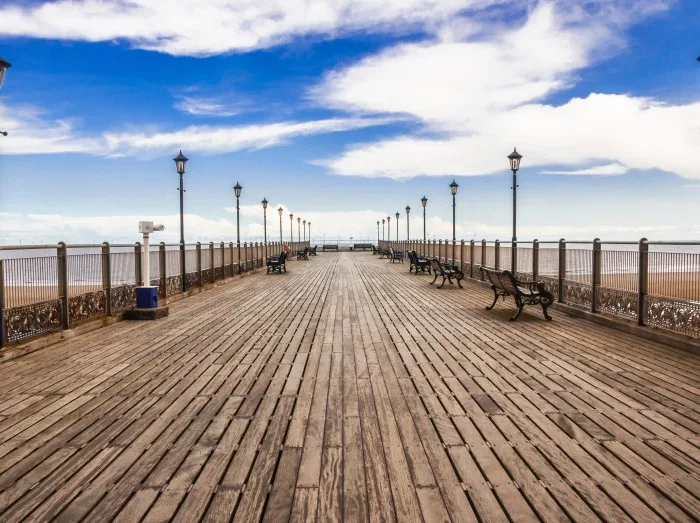 Wooden Skegness pier heading to the sea in the UK. Lamps, perspective, horizon and skies.