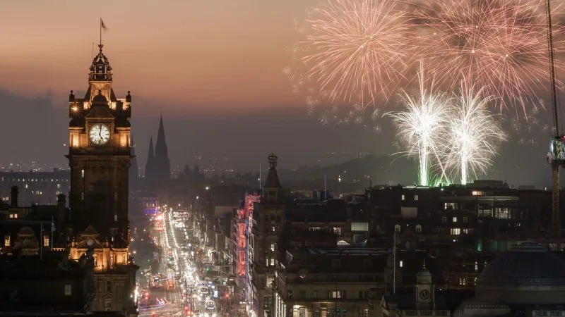 View of Princess Street, Edinburgh, from Calton Hill at dusk, with lights on and firework display in the sky. Scotland.
