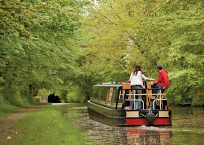 A couple enjoying a canal boat holiday on the Regency 2 Sophie in Napton on the Hill, Warwickshire, England, UK (NAPT-BH2233)