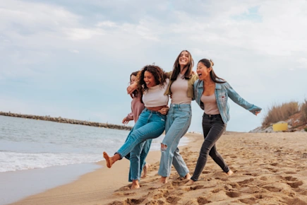 Four young women walking on the beach together and having fun