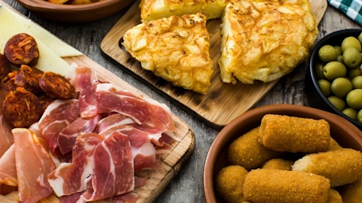 Traditional spanish tapas. Croquettes, olives, omelette, ham and patatas bravas on wooden table