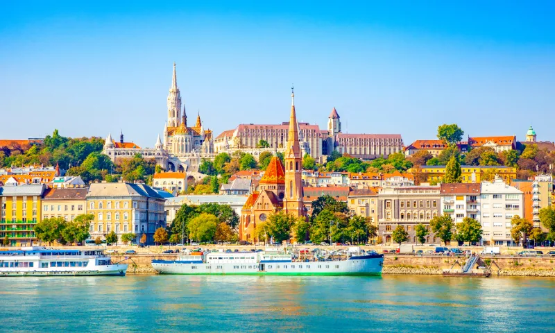 Gaze across the Danube to Budapest’s skyline, where Buda Castle crowns the hill in a golden glow above the river.