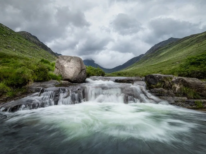 A small cascade alongside a large boulder in Glen Rosa on the Isle of Arran, Scotland. The valley is a typical glacier valley from the ice age