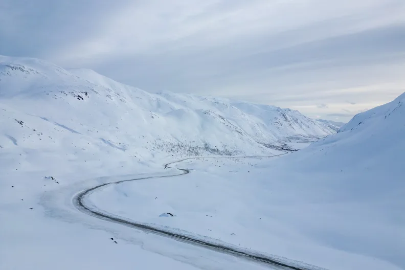 Endlose Straße durch eine winterliche Landschaft.
