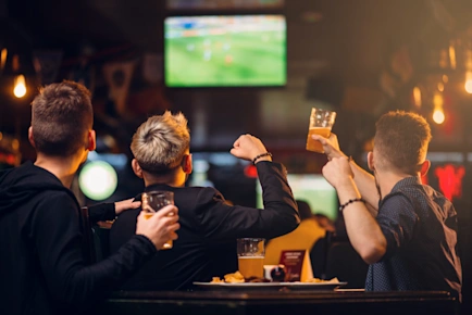 Group of friends cheering whilst watching a football match in a sports bar