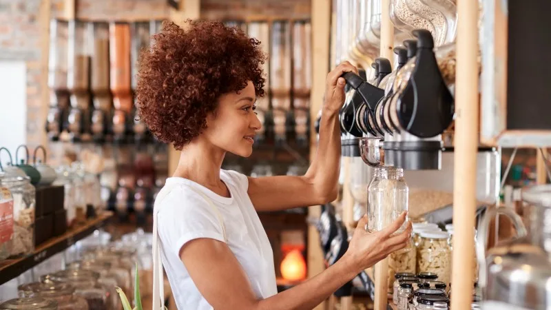 Woman Buying Cereals And Grains In Sustainable Plastic Free Grocery Store