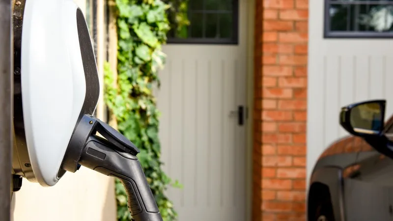 Electric car plugged in to charge outside home with power cable