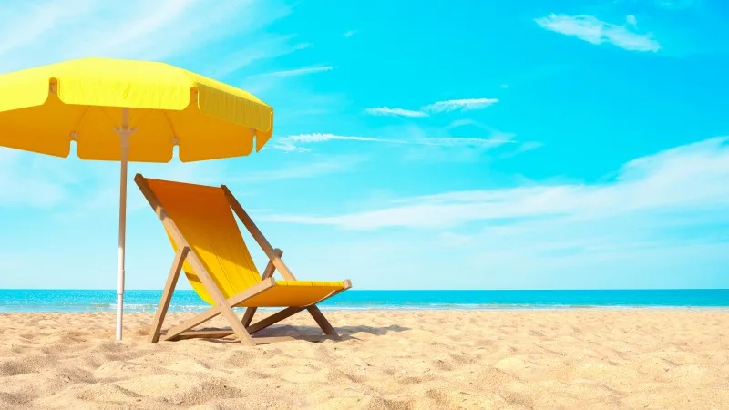 beach vacation with yellow parasol chair on blue sky