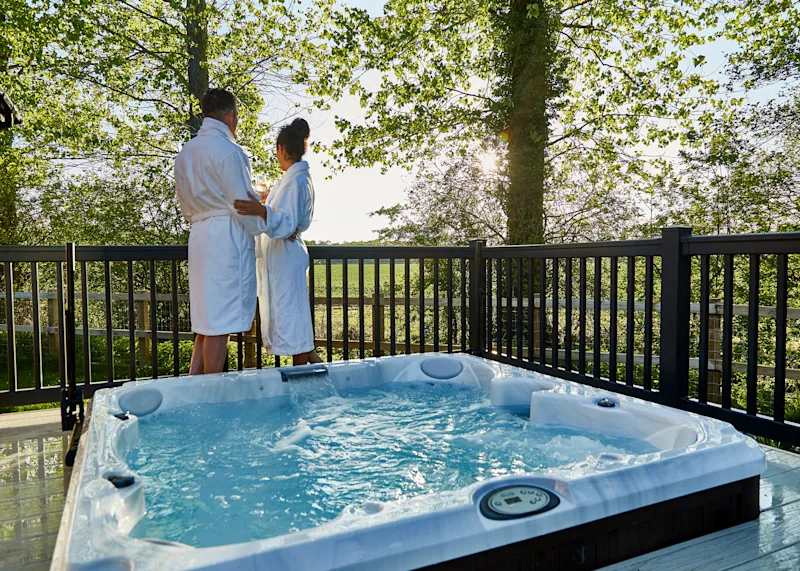 A couple relaxing in their hot tub lodge at Norfolk Woods Resort & Spa (NWRS), near King-s Lynn, Norfolk, England, UK