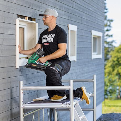 Työmies Tiklin asennustelineellä tekemässä ikkunaremonttia