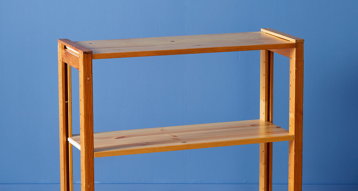 Vaalea puinen kaksitasohylly sinistä seinää vasten