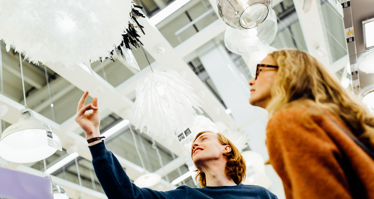 Kaksi asiakasta katselemassa valkoisia ja lasisia riippuvalaisimia valaisinliikkeessä.