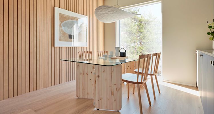 Puupaneeliseinäinen ruokailutila: lasipöytä, neljä tuolia, valkoinen lamppu, ikkuna metsään.