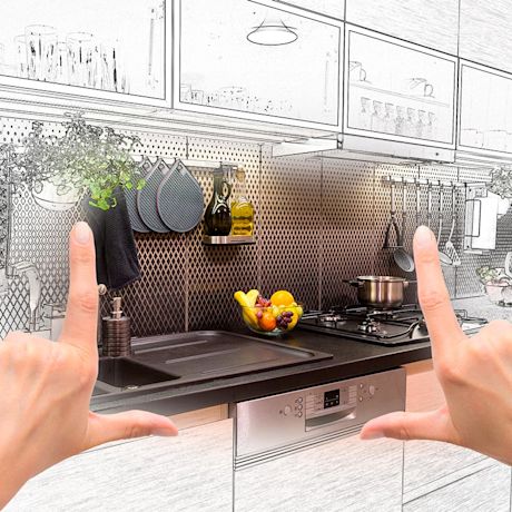 Kädet kehystävät modernin keittiön: musta työtaso, tiskiallas, hedelmäkulho ja ripustetut astiat