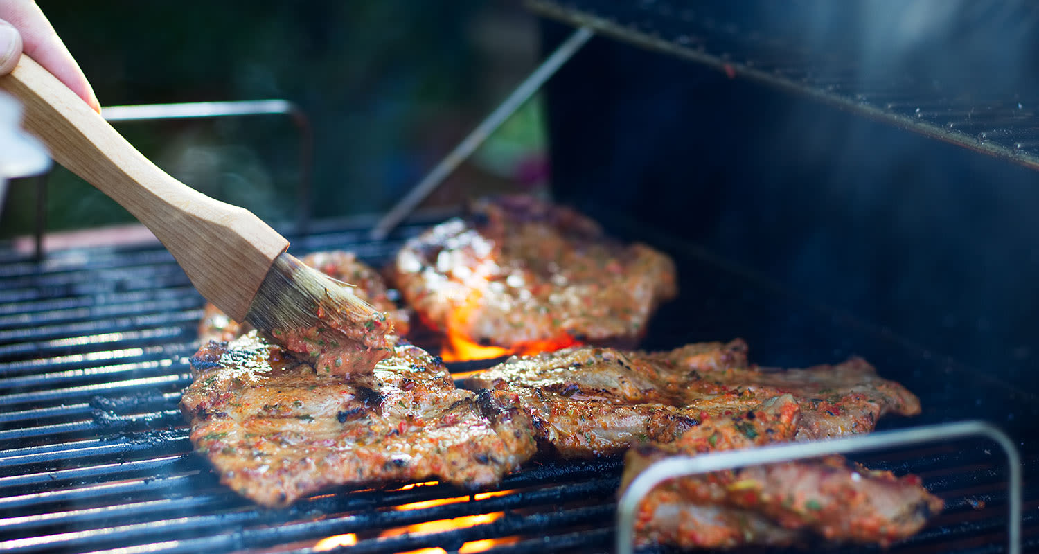 Puisella siveltimellä marinoituja pihvejä grilliritilällä oranssien liekkien yllä
