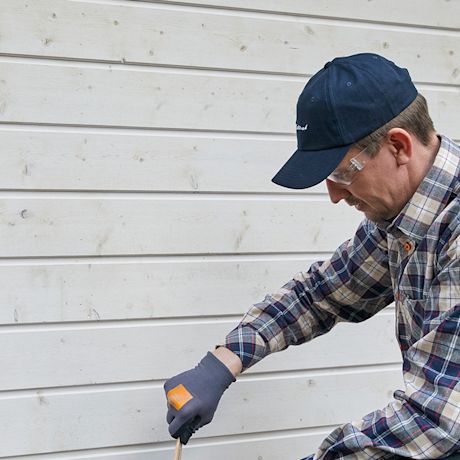 Mies maalaa talon ulkoseinää