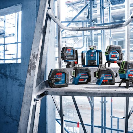 Betonihyllyllä sinisiä Bosch-laseritasoja rakennustelineiden edessä