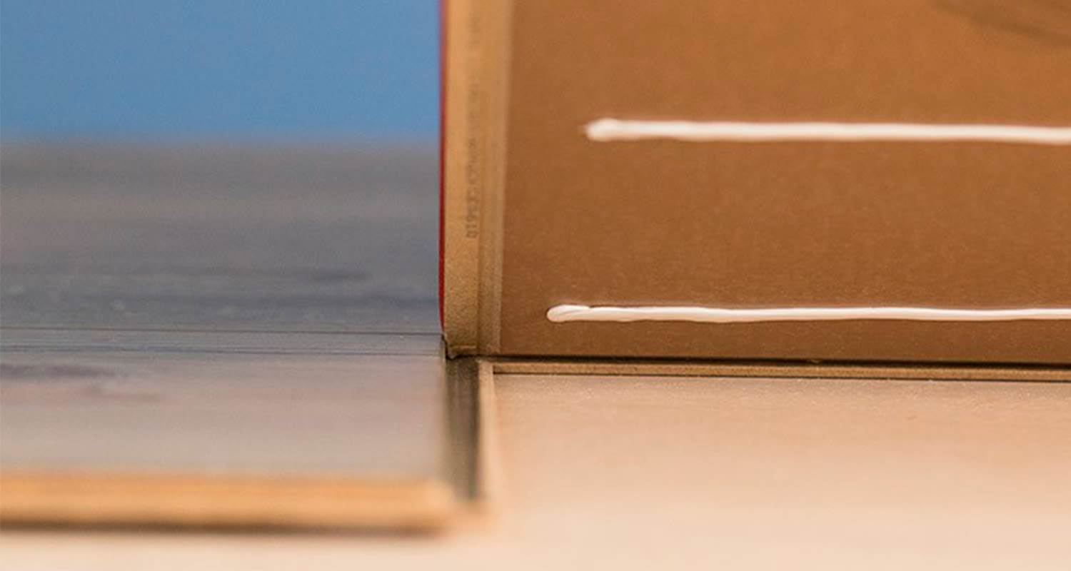 Lattialla harmaa ja beige paneeli, vieressä ruskea pystypaneeli valkoisilla viivoilla.