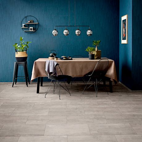 Tummansininen ruokahuone, harmaa laattalattia, ruskea pöytä, mustat tuolit, kattovalaisin, viherkasvit