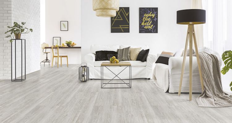 Skandinaavinen olohuone: valkoinen sohva, vaalea lattia, musta lattiavalaisin ja pöytä sitruunoilla.