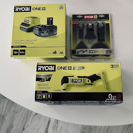 Pöydällä valmiina kokeiluun Ryobin akkumonitoimikone akkupaketin ja teräsarjan kera.