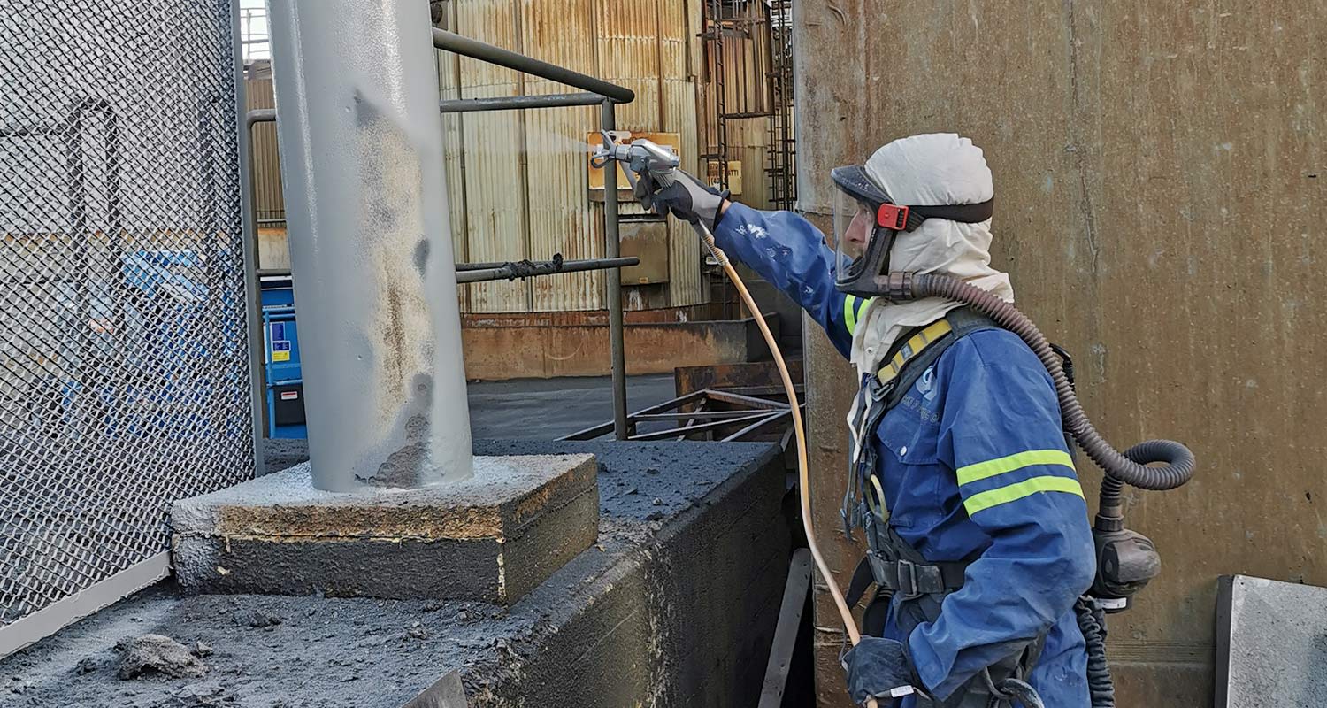 Työmies maalaa korkeapaineruisku Wagner PS 20 -mallilla tolppaa harmaaksi