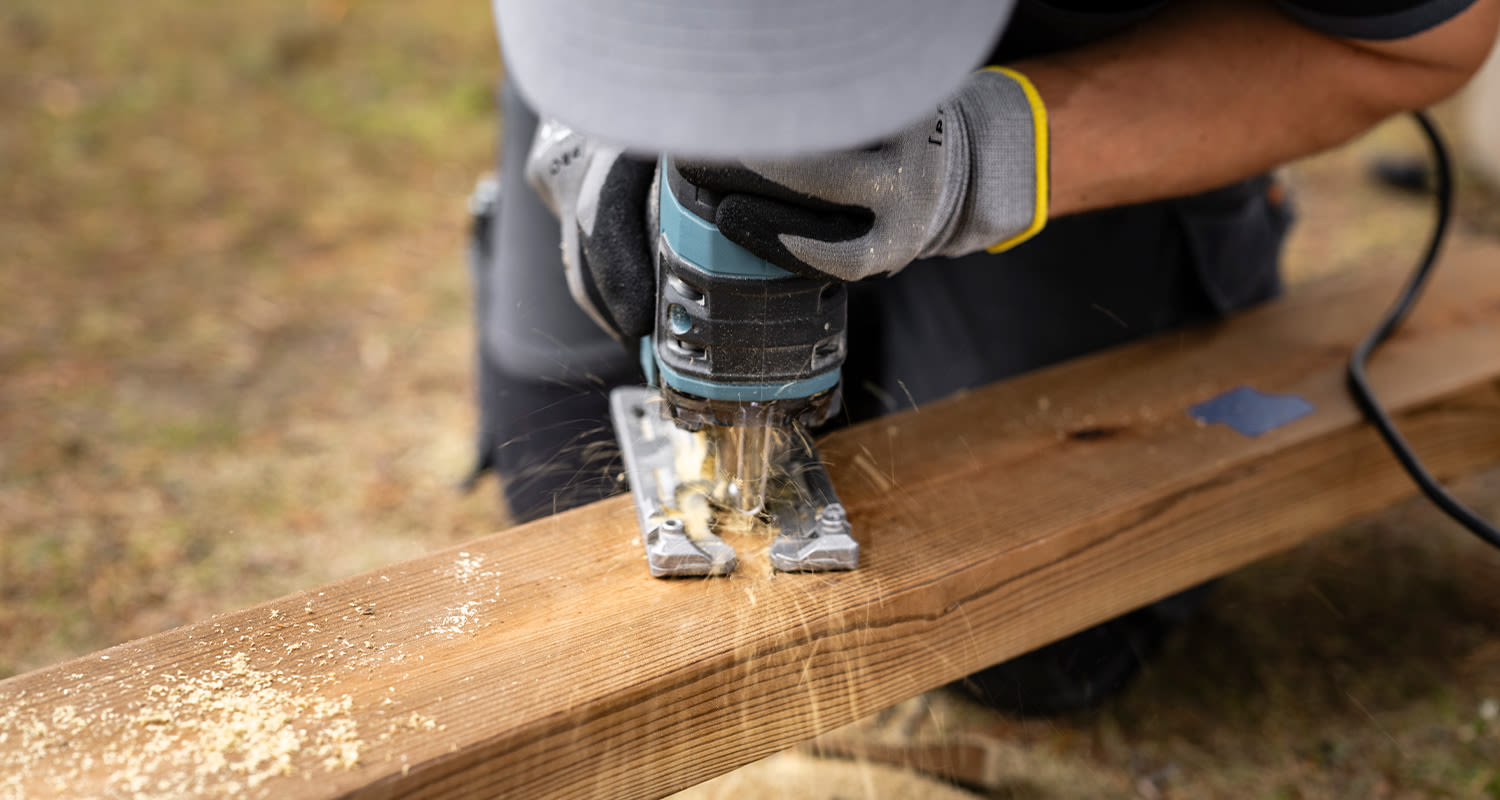 Tee itse terassikaide: Mies sahaa terassikaiteen alarunkopuuta sekä siihen tulevia pystypuiden lovia.