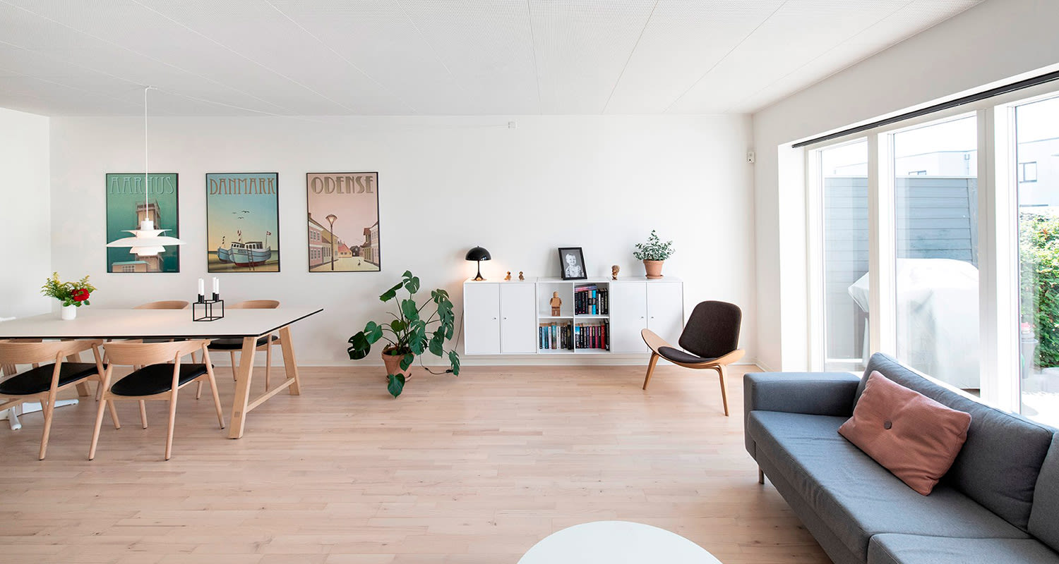 Vaalea olohuone, jossa valkoiset seinät ja pastellinsävyiset taulut seinällä