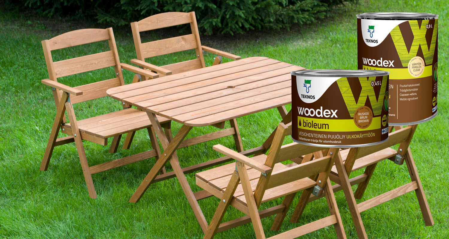 Vaalea puupöytä ja -tuolit vihreällä nurmikolla, edessä ruskeat Woodex-puuöljypurkit.