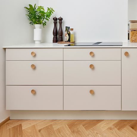 Puunväriset nuppivetimet vaaleissa keittiön alakaapeissa. Kuvan keittiö on Cello-keittiöiden valikoimista, joita myy K-Rauta.