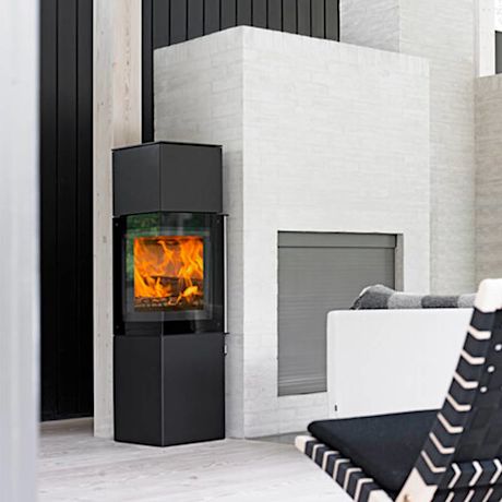 Modernissa olohuoneessa musta takka oransseilla liekeillä valkoista tiiliseinää vasten