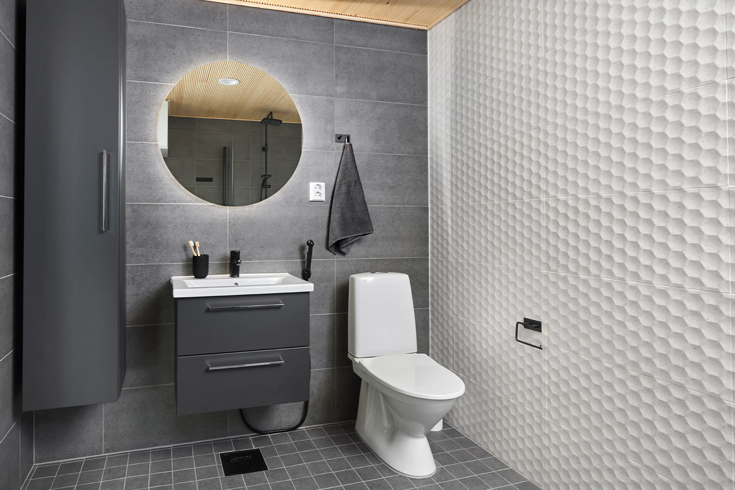 Harmaassa kylpyhuoneessa on Keskon valikoimista laatat ja kylpyhuonekalusteet.