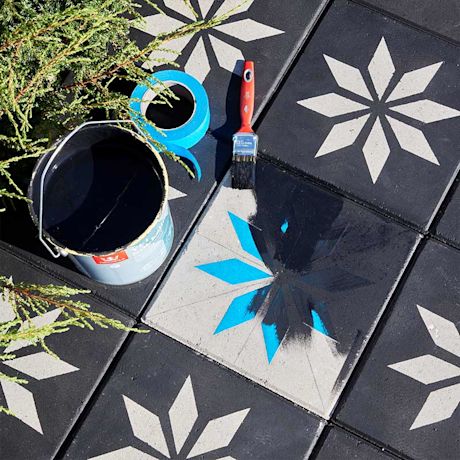 Musta-harmaa tähtikuviolaatta, keskellä sinivalkoinen maalaus, maalisuti ja maalipurkki