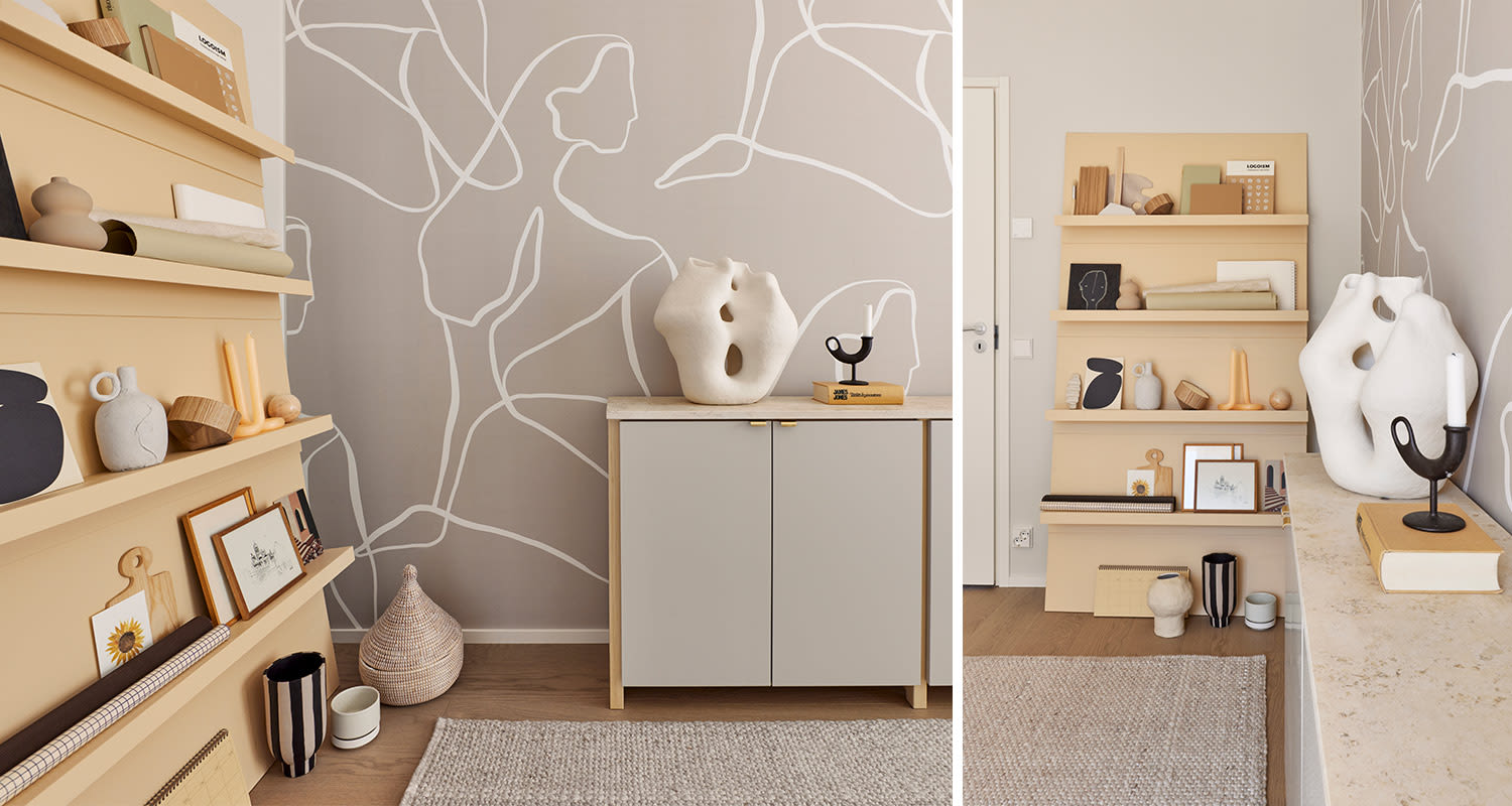 Keltainen hylly ja harmaa kaappi valkoisine veistoksineen abstraktikuviollisella seinällä